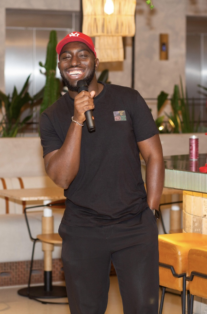 Rasheed on the mic in an FTBK T-shirt, hosting an event